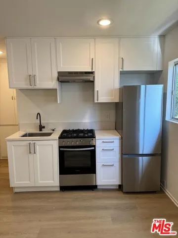 a kitchen with a refrigerator stove and white cabinets