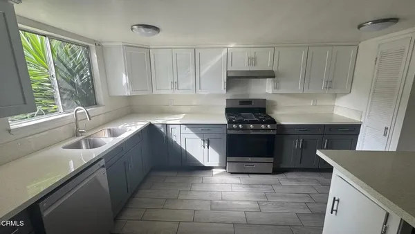 a kitchen with granite countertop a stove a sink and a microwave