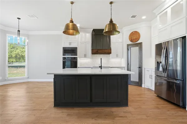 a kitchen with stainless steel appliances granite countertop a refrigerator a sink and a wooden floor