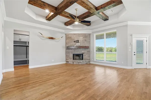 an empty room with wooden floor a ceiling fan and windows