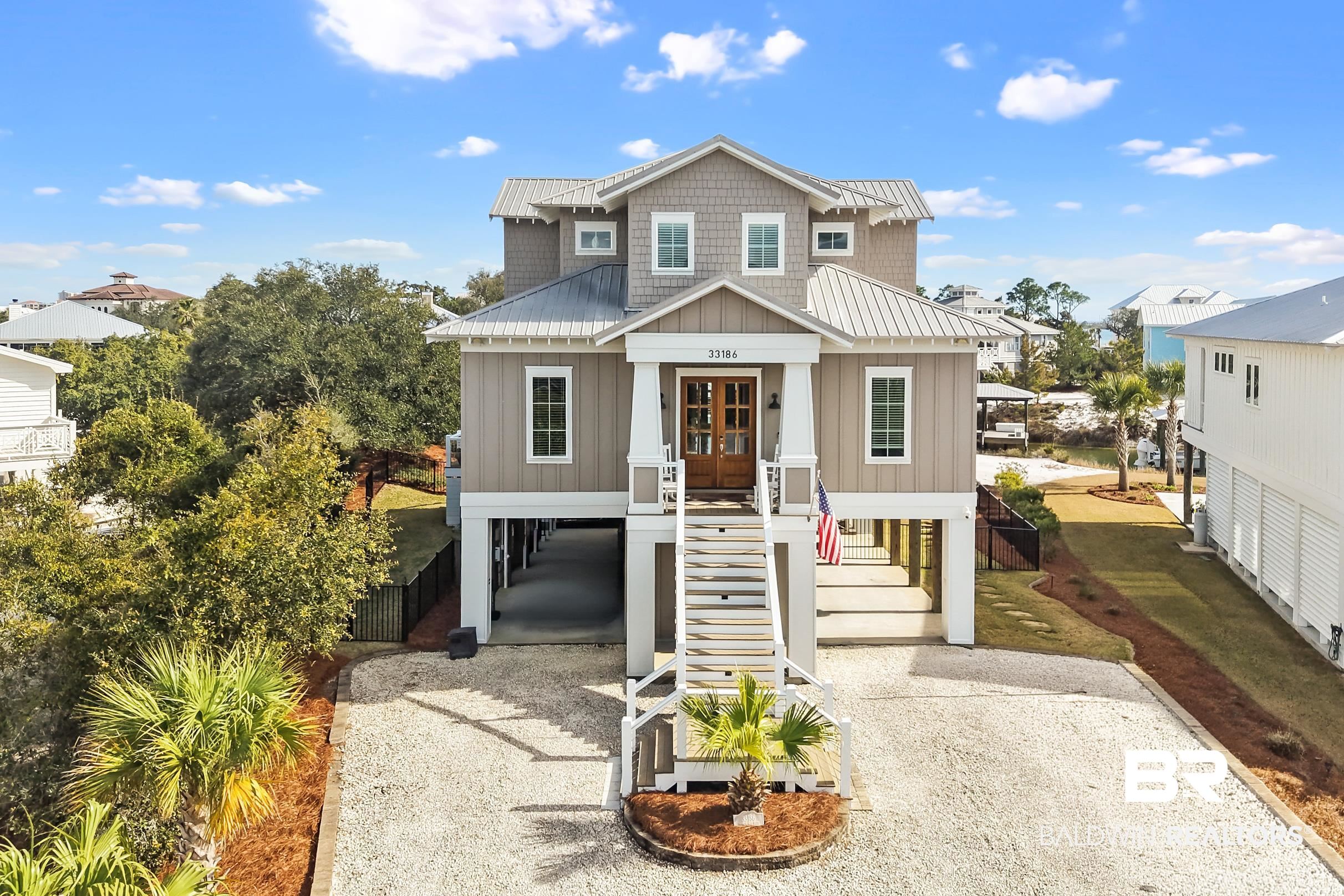 33186 Marlin Key Drive Orange Beach, AL 36561 - Photo 1 of 87 Raised beach house featuring a carport, board and batten siding, driveway, french doors, and a metal roof
