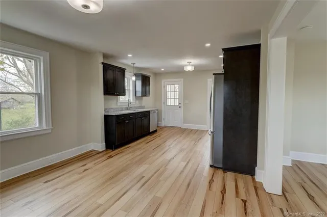 a view of kitchen and empty room with wooden floor