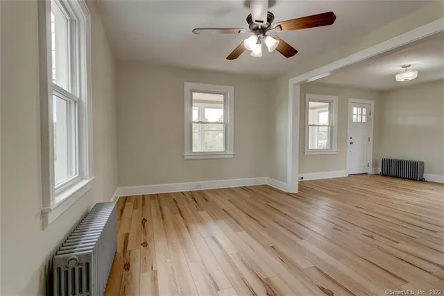 a view of empty room with wooden floor and fan