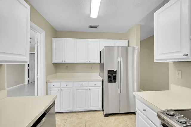 a kitchen with white cabinets and refrigerator