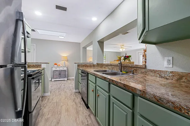 a kitchen with stainless steel appliances granite countertop a sink a stove and a refrigerator