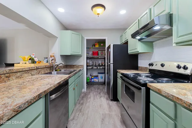 a kitchen with stainless steel appliances granite countertop a stove a sink and a refrigerator