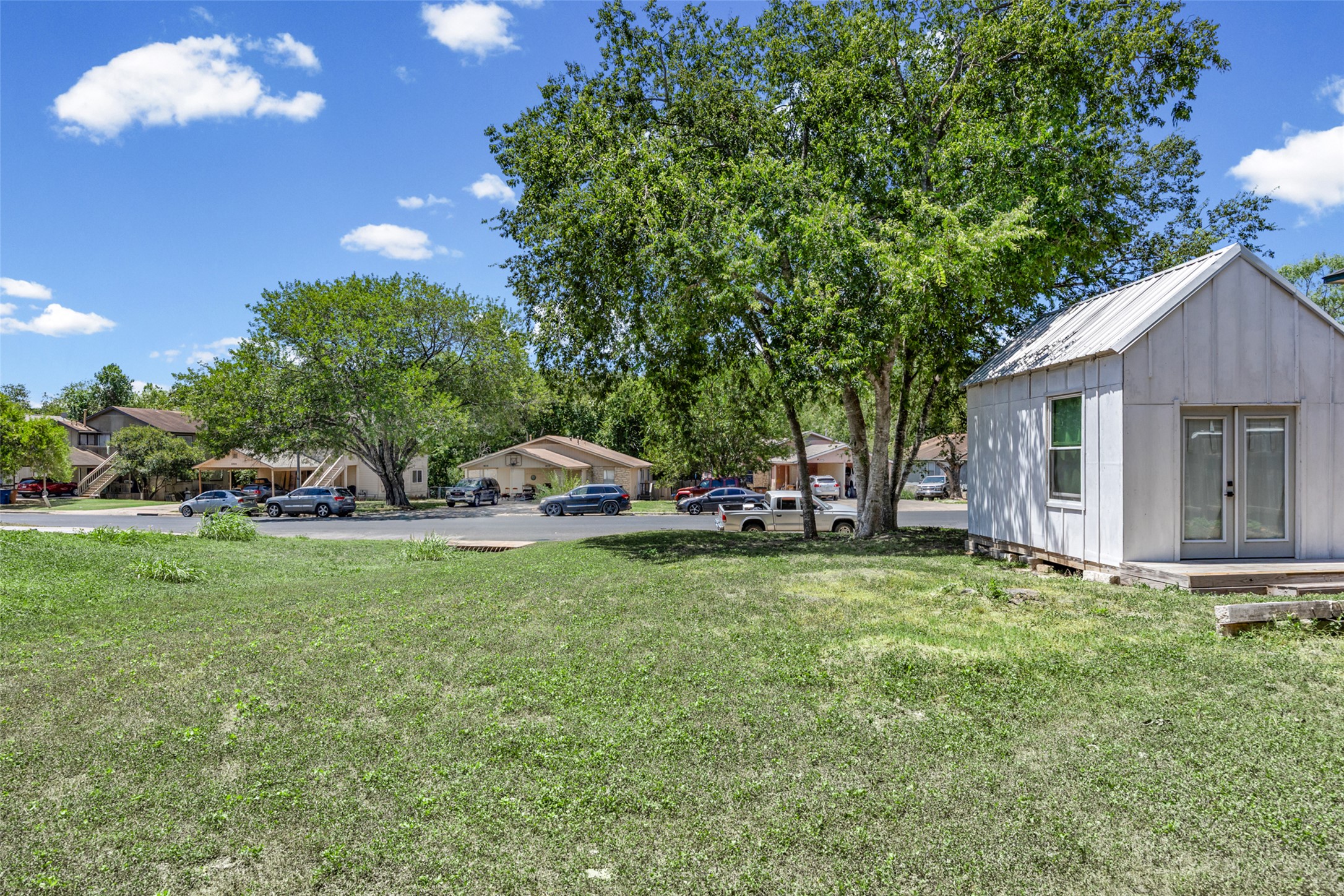 5706 Spring Meadow Road Austin, TX 78744 - Photo 6 of 11 A spacious grassy lawn features mature shade trees and a versatile detached outbuilding.