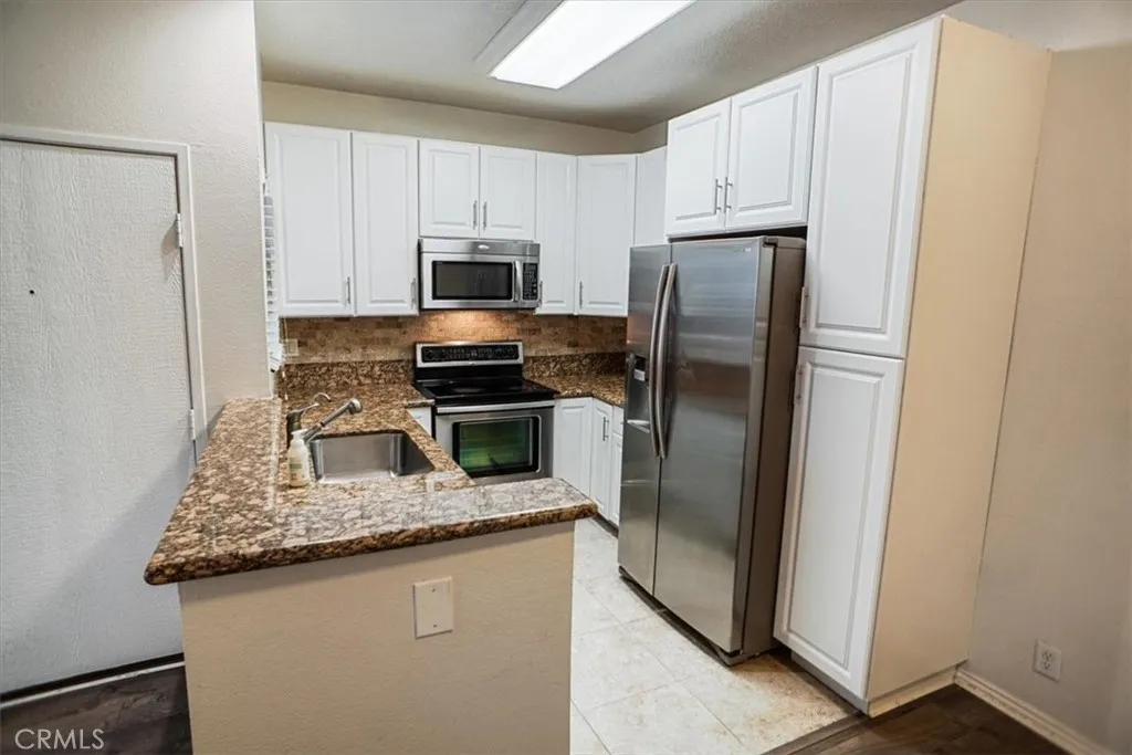 27646 Susan Beth Way Saugus, CA 91350 - Photo 2 of 12 a kitchen with refrigerator a microwave a sink and cabinets