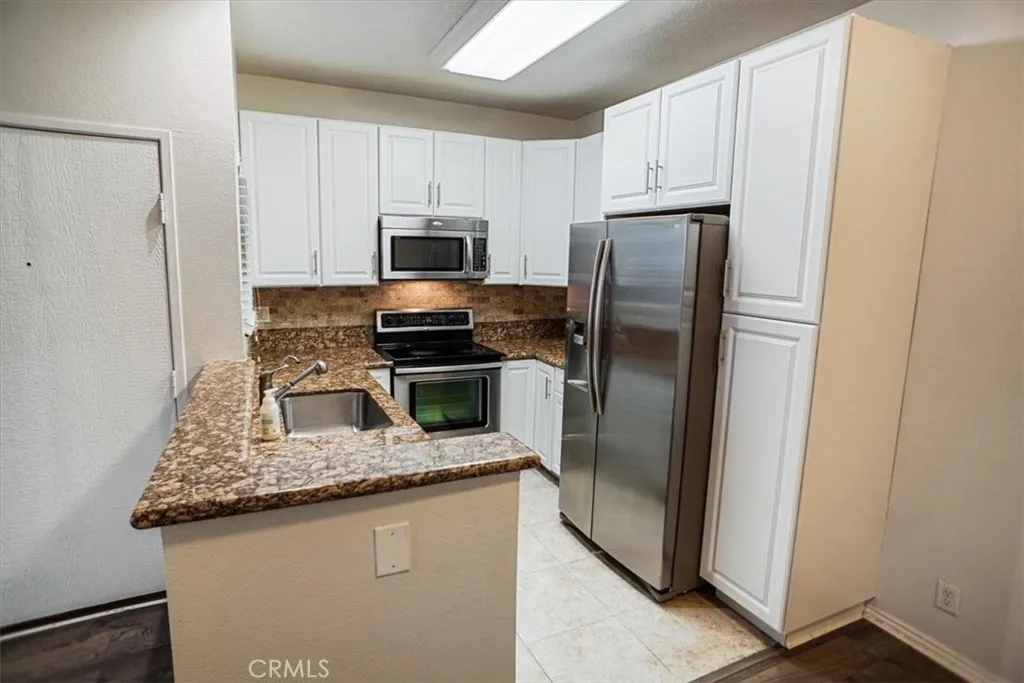 27646 Susan Beth Way Saugus, CA 91350 - Photo 2 of 12 a kitchen with refrigerator a microwave a sink and cabinets