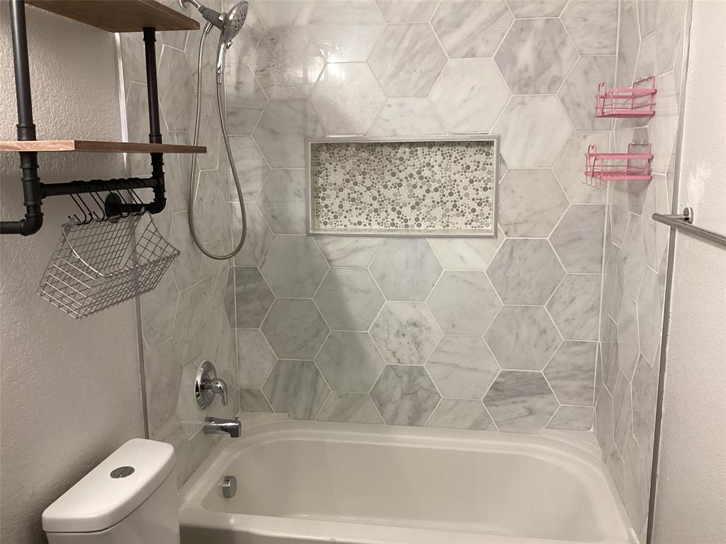 10320 Point Lobos Trail Fort Worth, TX 76177 - Photo 22 of 33 Bathtub with hexagon-patterned wall tile, integrated tiled niche, chrome shower hardware, and a white toilet