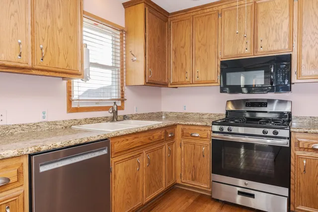 a kitchen with stainless steel appliances granite countertop a sink a stove and a microwave oven with cabinets