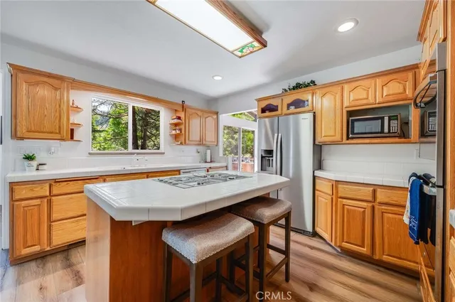 a kitchen with stainless steel appliances granite countertop a table chairs sink refrigerator and granite counter top