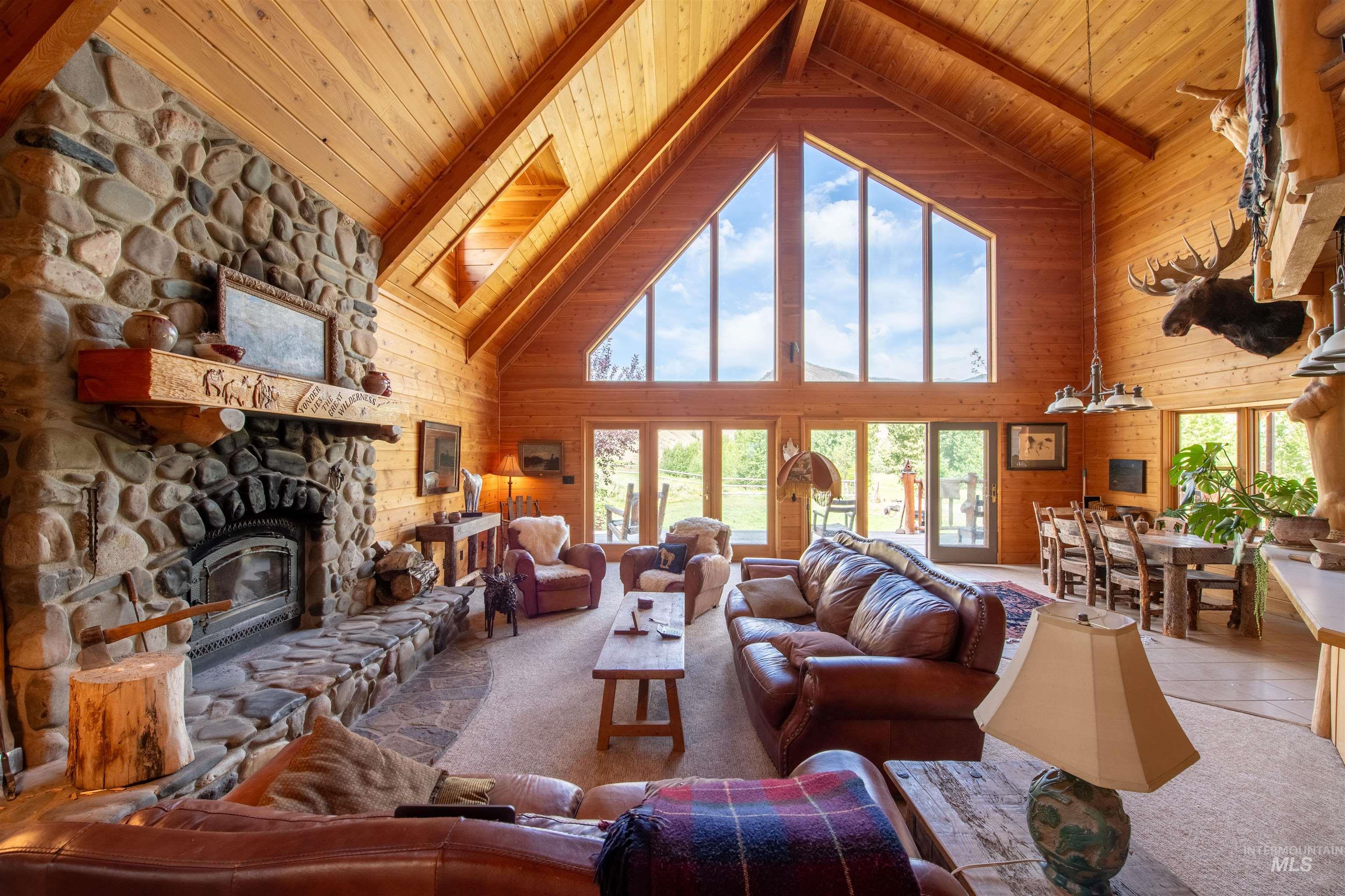 9885 Challis Creek Road Challis, ID 83226 - Photo 10 of 48 Tiled living area featuring high vaulted ceiling, wooden walls, a wood ceiling with exposed beams, a fireplace, and carpet flooring