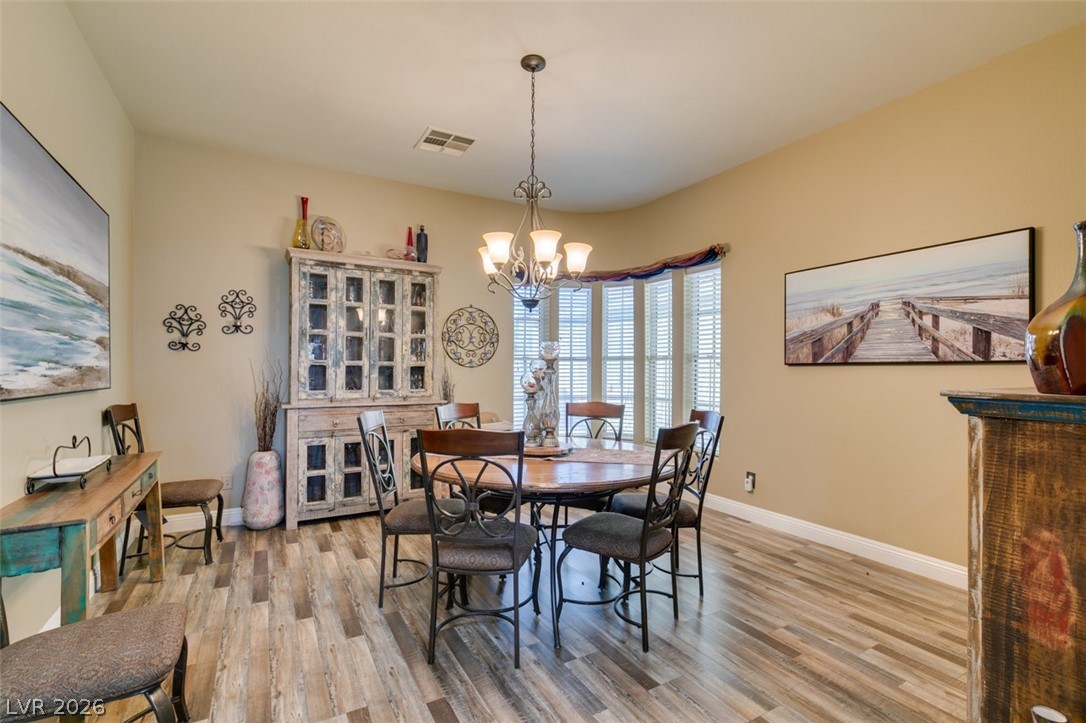 7524 Midnight Rambler Street Las Vegas, NV 89149 - Photo 23 of 51 A well-lit dining area featuring a bay window and elegant wood flooring.