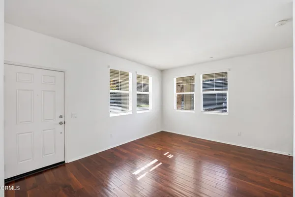 a view of an empty room with wooden floor and stairs