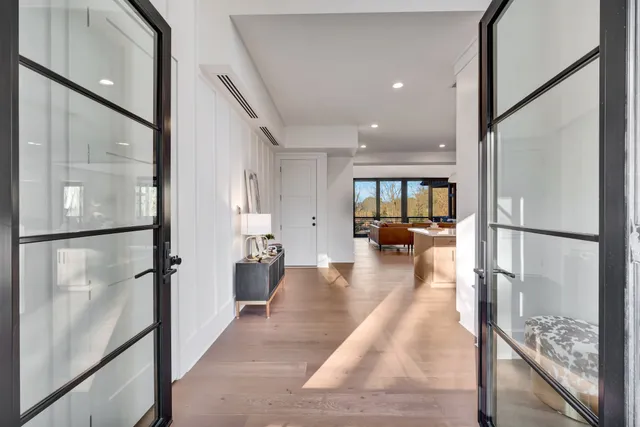 a kitchen with stainless steel appliances granite countertop a sink a stove a refrigerator and white cabinets with wooden floor