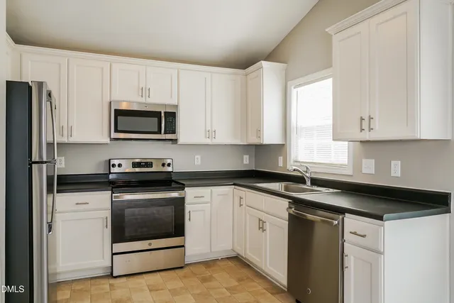 a kitchen with white cabinets and stainless steel appliances
