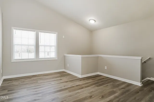 an empty room with wooden floor and window