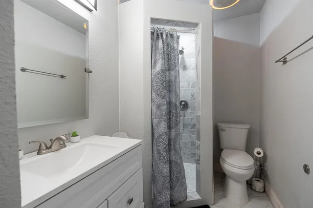a bathroom with a granite countertop sink toilet and shower