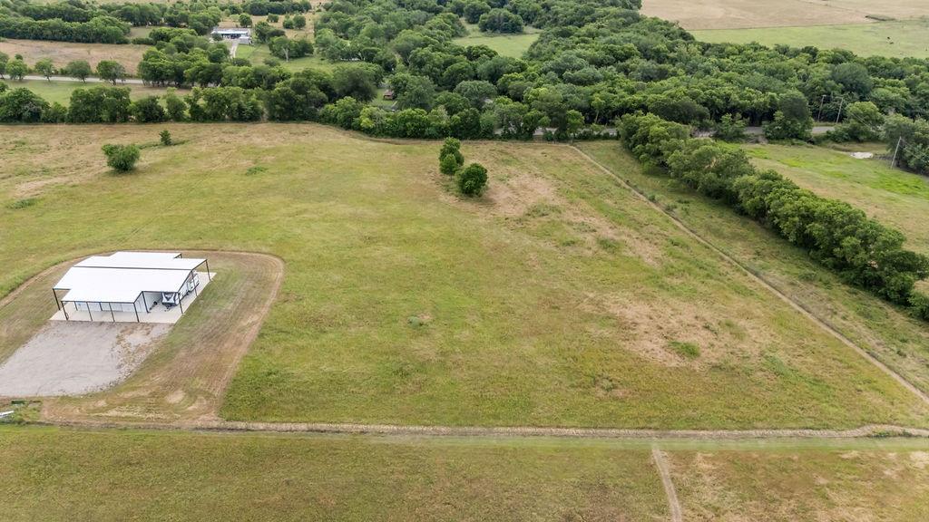 1161 Alsdorf Road Ennis, TX 75119 - Photo 10 of 28 Expansive parcel featuring a modern metal-roofed structure with an extended covered patio, surrounded by open grassland and mature tree lines