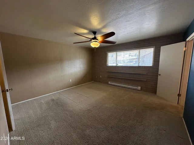 an empty room with windows and fan