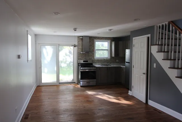 a kitchen with granite countertop a refrigerator a sink and dishwasher with wooden floor
