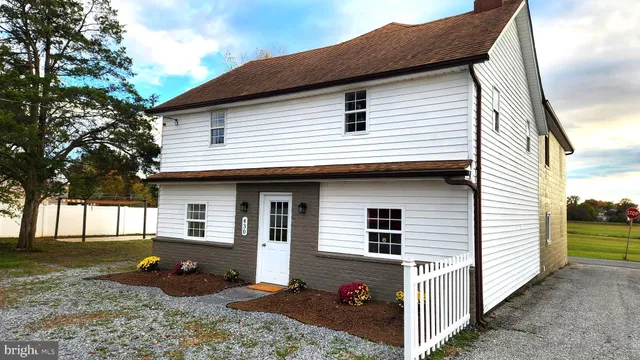 a view of a white house with a small yard and large tree