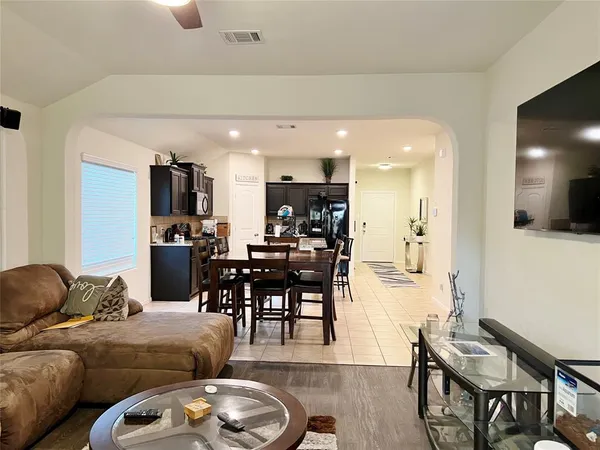 a living room with furniture kitchen view and a wooden floor