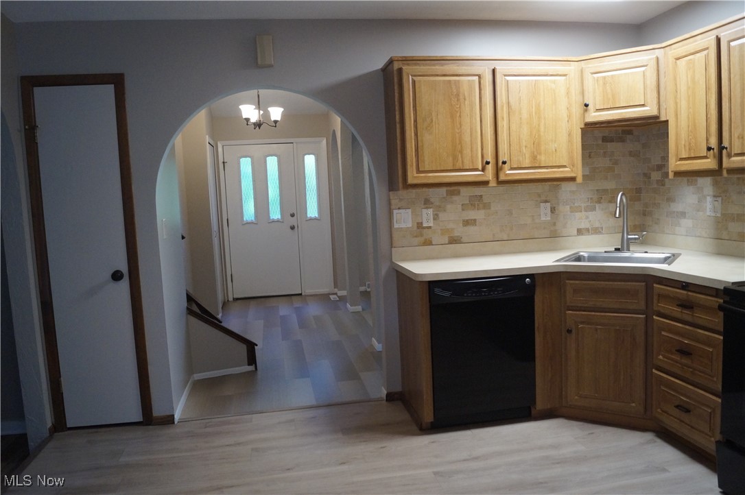 7372 Liberty Road Solon, OH 44139 - Photo 5 of 33 Kitchen featuring light countertops, black appliances, decorative backsplash, and light wood-style luxury vinyl plank flooring with pantry
