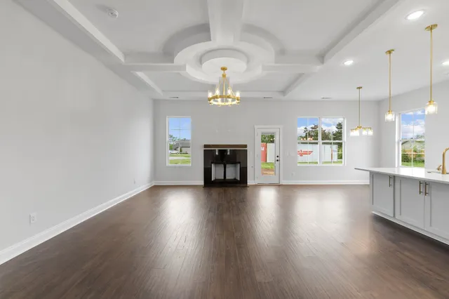 an empty room with wooden floor chandelier and windows