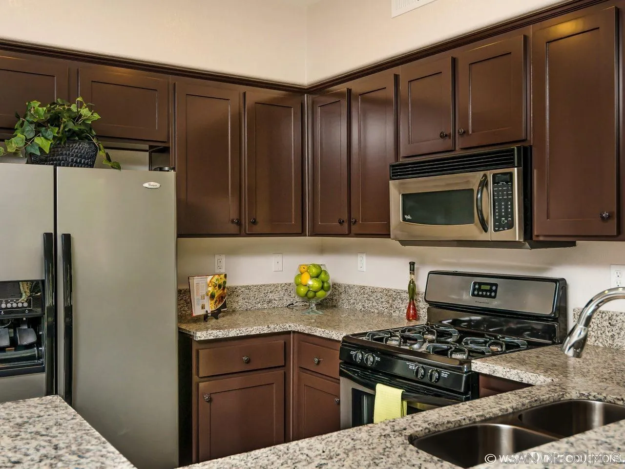 2145 Caminito Elda, Unit 104 Chula Vista, CA 91915 - Photo 4 of 9 a kitchen with granite countertop stainless steel appliances a stove a microwave a refrigerator and cabinets