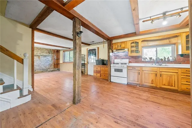 a large kitchen with stainless steel appliances wooden floor and cabinets