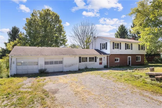 a front view of a house with a yard covered with trees