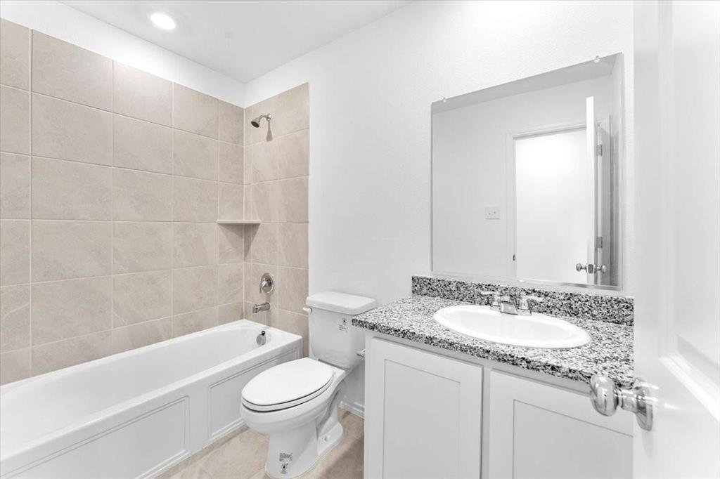 211 Herman Lane Princeton, TX 75407 - Photo 19 of 40 a bathroom with a granite countertop sink a toilet a mirror a bathtub and shower