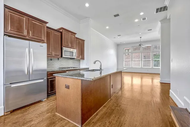 a kitchen with stainless steel appliances granite countertop a refrigerator a sink dishwasher a stove with wooden floor and cabinets