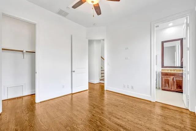 an empty room with wooden floor and way to kitchen