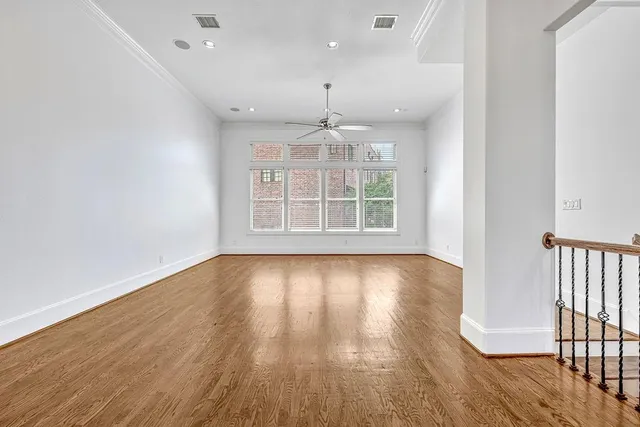 an empty room with wooden floor chandelier and windows