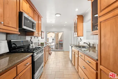 a kitchen with stainless steel appliances granite countertop a stove a sink and a microwave