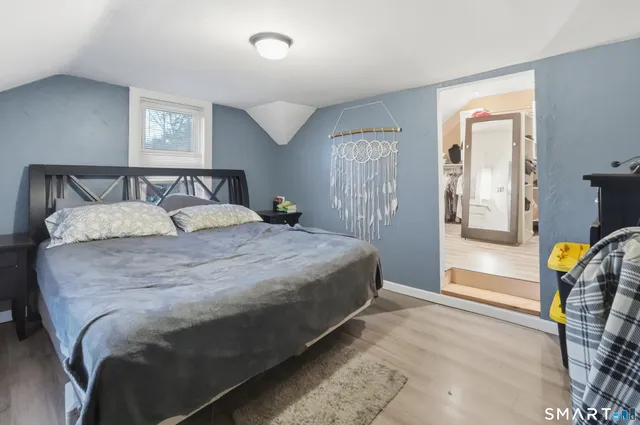 a bedroom with a bed and a lamp on dresser next to a window