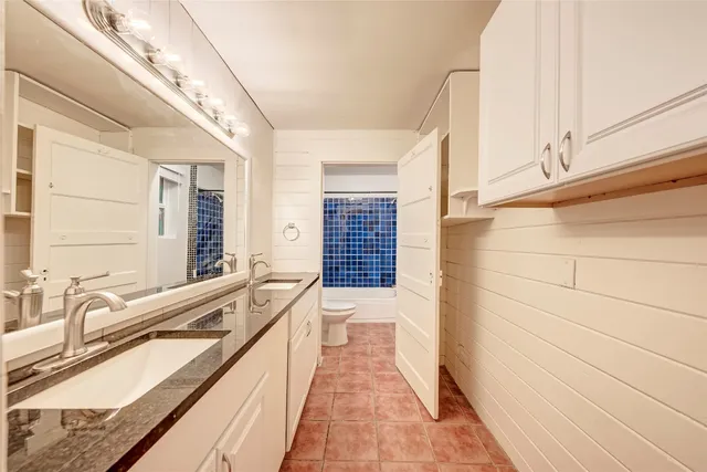 a bathroom with a granite countertop sink a large mirror and a bathtub