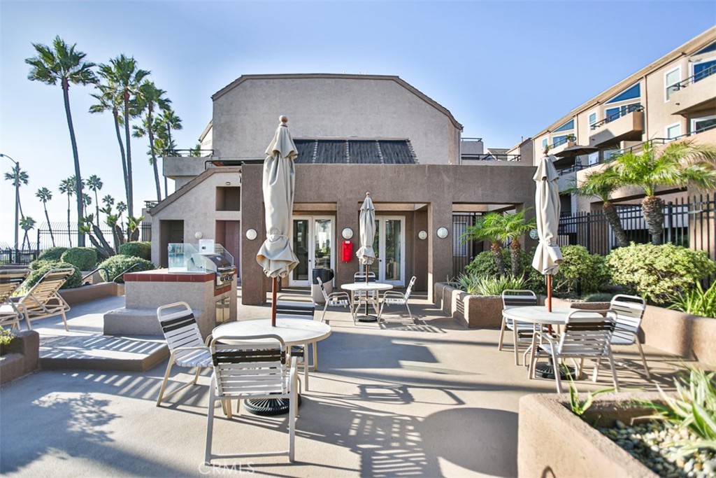 1200 Pacific Coast Highway, Unit 423 Huntington Beach, CA 92648 - Photo 12 of 40 a view of a patio with couches table and chairs potted plants and palm tree