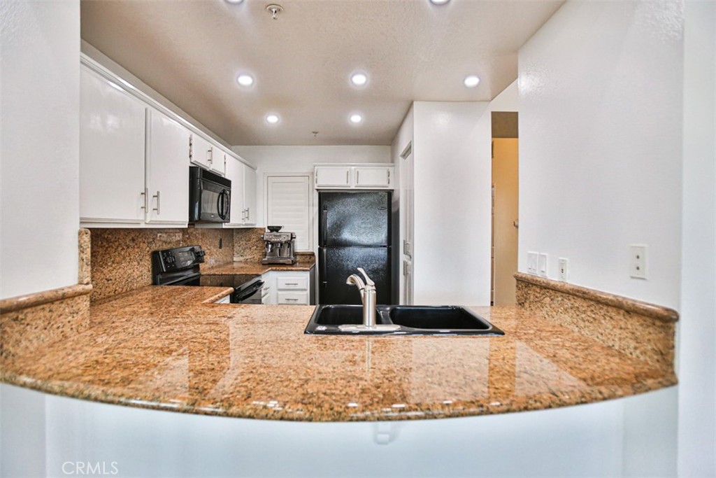 1200 Pacific Coast Highway, Unit 423 Huntington Beach, CA 92648 - Photo 33 of 40 a kitchen with sink a refrigerator and microwave