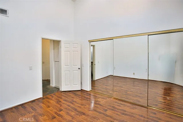 a view of an empty room with wooden floor and closet