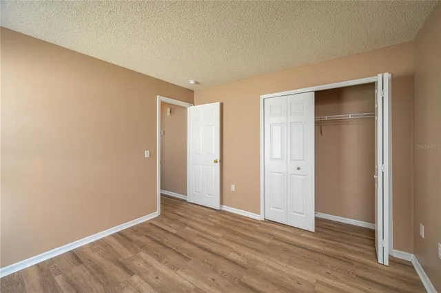 a view of an empty room with wooden floor & closet
