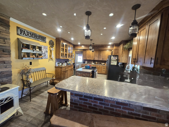34200 Coulam Road Swan Lake, ID 83281 - Photo 9 of 24 Spacious kitchen featuring extensive wood cabinetry, an island with a built-in cooktop, and a breakfast bar with brick detailing