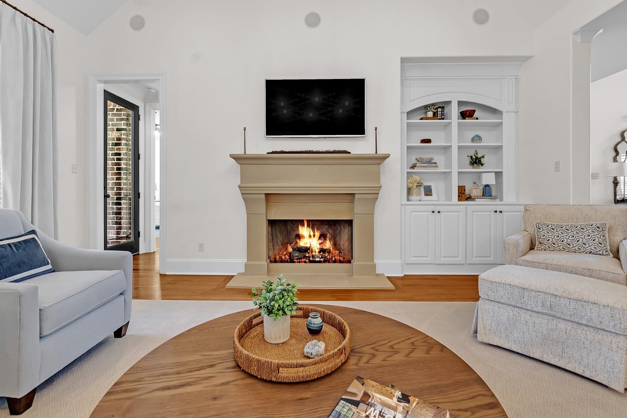 3246 North Hartwell Ridge Drive Collierville, TN 38017 - Photo 14 of 40 Stone mantelpiece framing a fireplace, integrated built-in shelving, vaulted ceiling with recessed lighting, wood-finish flooring, and a glass-paned door