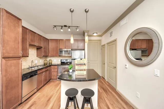 a kitchen with stainless steel appliances granite countertop a stove a refrigerator a dining table and chairs with wooden floor