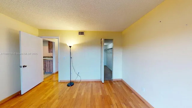 a view of an empty room with wooden floor and doors