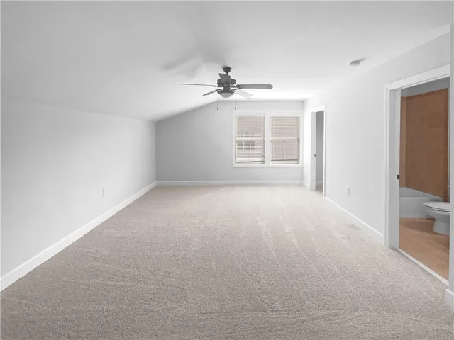 an empty room with chandelier fan and windows