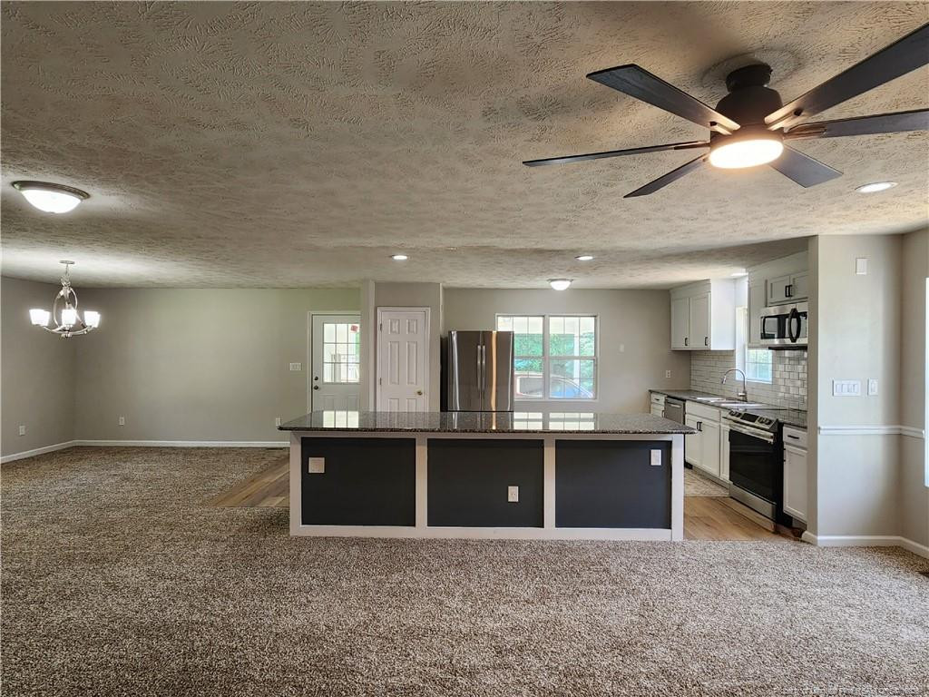 5444 Rockfish Road Raeford, NC 28376 - Photo 10 of 37 an open kitchen with kitchen island a stove and a refrigerator